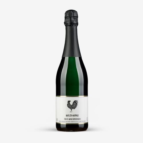 Eine Flasche Sekt mit einem dunkelgrünen Körper, schwarzer Folie am Hals und einem weißen Etikett mit einem schwarzen Hahn und Text.