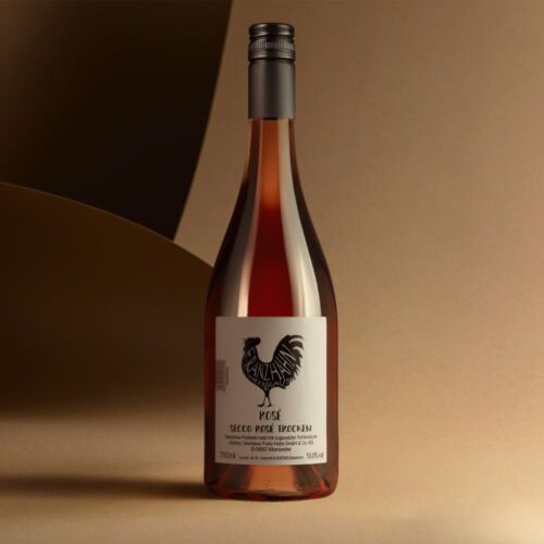 Eine Flasche Rosé Secco mit schwarzem Hahn-Logo und weißem Etikett steht auf einer beigen Fläche vor einem sanft beleuchteten abstrakten Hintergrund in Beige und Braun.