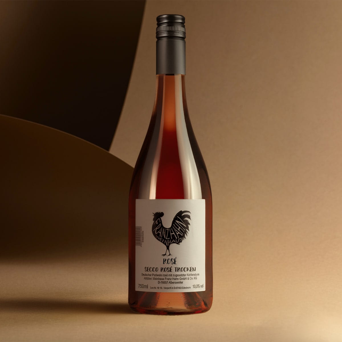 Eine Flasche Rosé Secco mit schwarzem Hahn-Logo und weißem Etikett steht auf einer beigen Fläche vor einem sanft beleuchteten abstrakten Hintergrund in Beige und Braun.